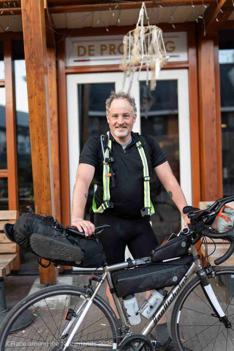 Jesse Burkunk at the finish of the Race around the Netherlands, next to his loaded bikepacking bike